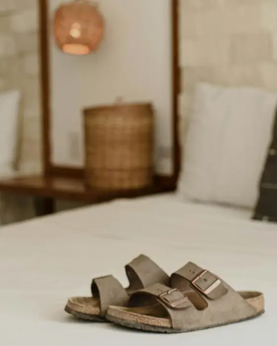 Bed with linen sheets next to a light wall